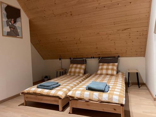two beds in a room with a wooden ceiling at Mazurska Stodoła Na Półwyspie Pilchowskim in Pilchy
