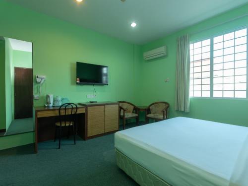 Schlafzimmer mit einem Bett, einem Schreibtisch und einem TV in der Unterkunft Royal Hotel in Keningau