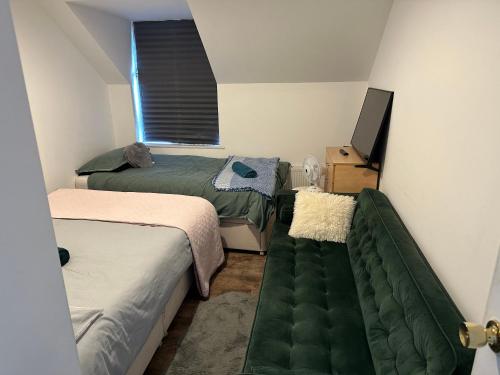 - une petite chambre avec 2 lits et un canapé dans l'établissement Wembley Area Serviced Apartments, 15mins to Central London, à Londres