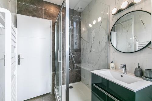 La salle de bains est pourvue d'une douche, d'un lavabo et d'un miroir. dans l'établissement MBA Splendide Appart - Montreuil 5 - Proche Vincennes, à Montreuil