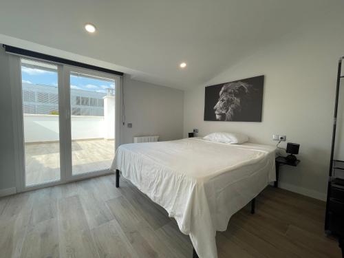 a white bedroom with a bed and a large window at manresa universidad in Manresa