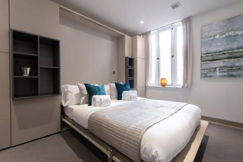 a bedroom with a large white bed with blue pillows at Central Reading Designer Studio in Reading