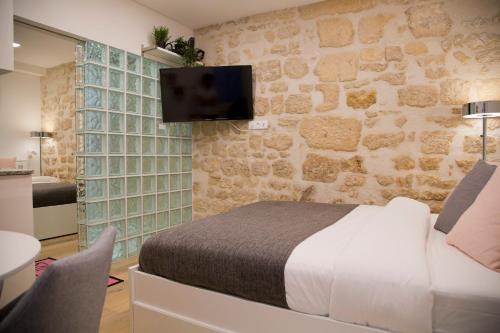 - une chambre avec un lit et une télévision sur un mur en pierre dans l'établissement Dauphine Chic & Charme, à Paris