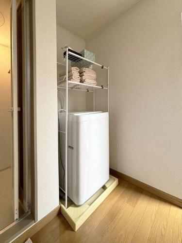 a small kitchen with a white refrigerator in a room at エスポアール新町Ⅵ(101) in Hanabatachō