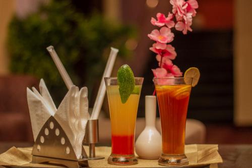 two cocktails sitting on a table with flowers at Amritara The Avadh in Badrīnāth