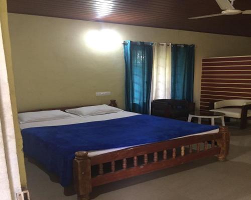 a bedroom with a large bed with a blue blanket at Hasiru Farms Homestay by StayApart in Mudigere