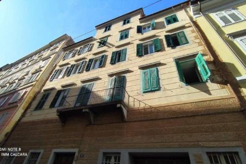 een hoog gebouw met groene luiken en een balkon bij Galleria sul Mare in Trieste