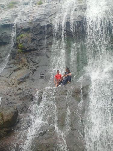 two people sitting in front of a waterfall at Shrushtiban farms in Dhamni
