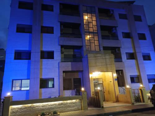 um edifício com luzes azuis à noite em Rimini Furnished Apart. em Amã