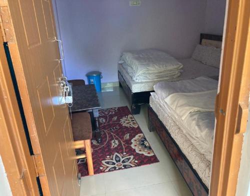 een kamer met 2 bedden, een bureau en een deur bij Amardeep Homestay by StayApart in Ukhimath