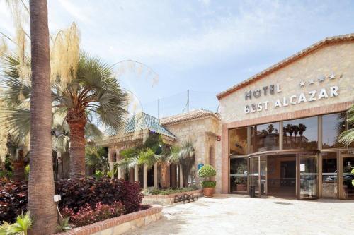 um hotel com uma palmeira em frente a um edifício em Hotel Best Alcázar em La Herradura