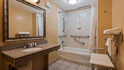 a bathroom with a sink and a shower and a tub at SureStay Plus by Best Western Covington in Covington
