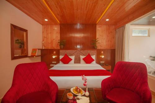 a bedroom with a bed and two red chairs at Amritara The Avadh in Badrīnāth