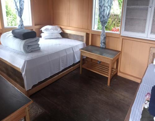 Cette chambre comprend 2 lits, une table et 2 fenêtres. dans l'établissement Rinzeebong Homestay by StayApart, à Mangan