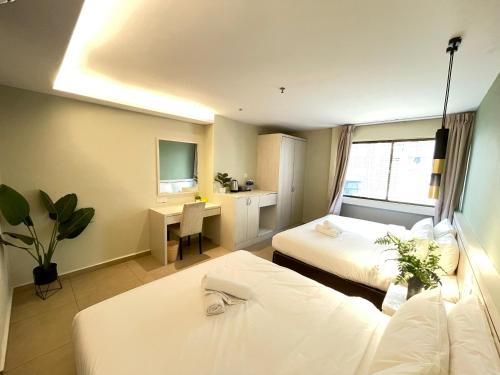 Habitación de hotel con 2 camas y escritorio en Swing & Pillows - Sungei Wang Hotel Bukit Bintang, en Kuala Lumpur