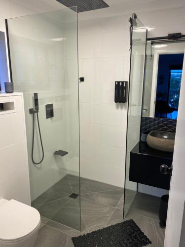 a bathroom with a shower with a toilet and a sink at Beach House in Yeppoon