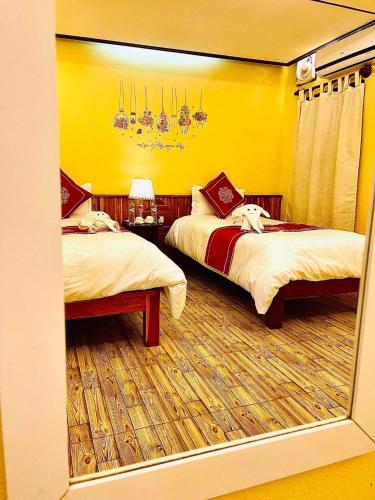 a bedroom with two beds and a yellow wall at Vieng Savanh II Hotel in Luang Prabang