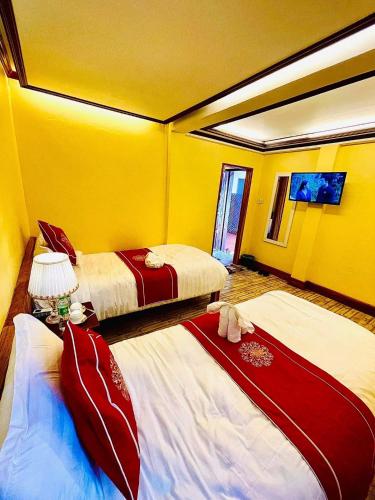 two beds in a room with yellow walls at Vieng Savanh II Hotel in Luang Prabang