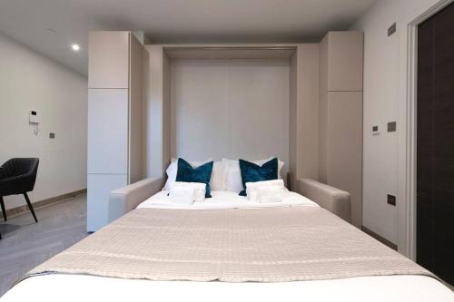 a bedroom with a large white bed with blue pillows at Urban Delight Central Reading Studio CHRL F8 in Reading