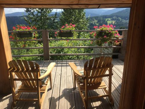 two chairs and a table on a deck with flowers at LES BALCONS DU PHENY LE REFUGE in Gérardmer