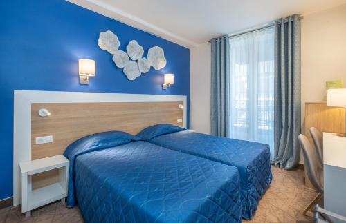 una camera da letto blu con un letto e una finestra di Hotel Terminus Montparnasse a Parigi