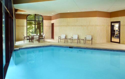 a swimming pool with chairs and tables in a building at Hilton Atlanta Northeast in Norcross