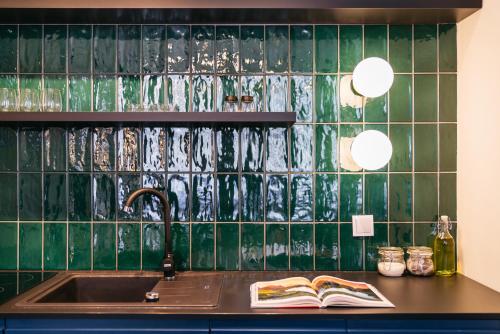 a kitchen with a sink and a green tiled wall at Estery12 - LoftAffair Collection in Krakow