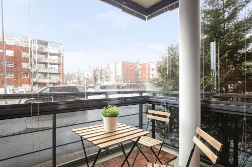 balcón con mesa de madera, sillas y ventana en Kotimaailma - Viihtyisä saunallinen kaksio, Leppävaara, en Espoo