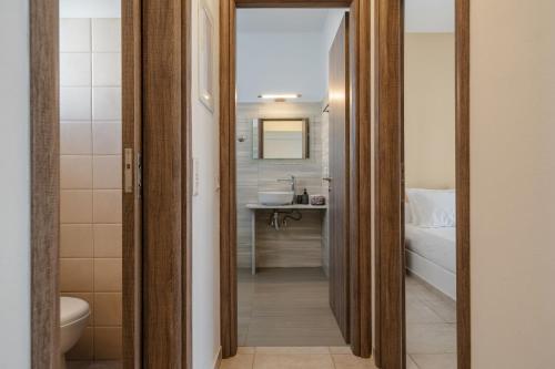 een badkamer met een wastafel, een toilet en een spiegel bij Evripus Suites in Kastraki Naxou