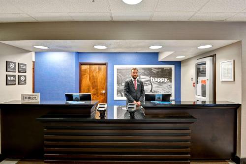a man in a suit standing at a reception desk at Hampton Inn State College in State College