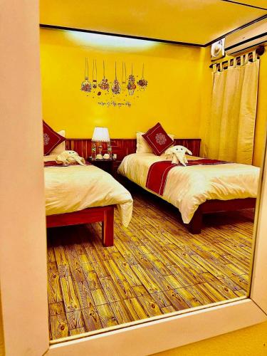 a bedroom with two beds and a yellow wall at Vieng Savanh II Hotel in Luang Prabang