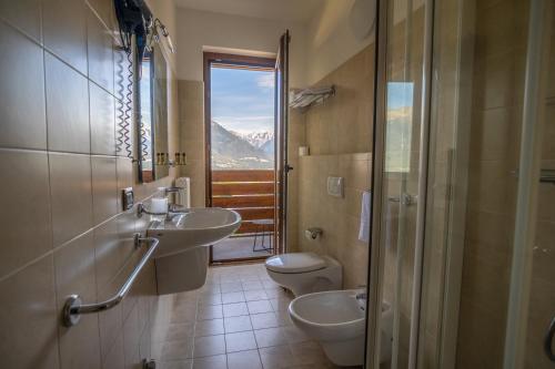 a bathroom with two sinks and a toilet and a window at Una Finestra Sulle Alpi in Bema