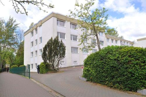 een groot wit gebouw in een straat naast een struik bij Bett u Butze Timmendorfer Strand Ferienwohnung in Timmendorfer Strand