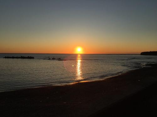 a sunset on the beach with the sun setting at MARINE-Q in Inami
