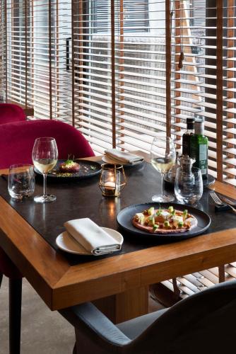 a wooden table with two plates of food and wine glasses at Radisson Blu Hotel Milan in Milan