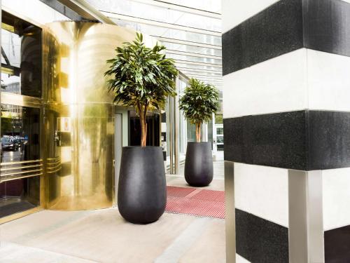 Dois grandes vasos pretos com árvores na entrada. em Radisson Blu Plaza Hotel, Oslo em Oslo