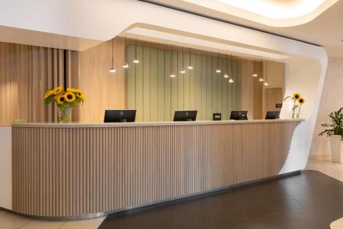 a lobby with a reception desk with chairs and flowers at Park Inn by Radisson Krakow in Kraków