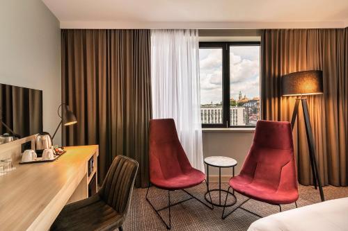 una camera d'albergo con sedie rosse, scrivania e finestra di Park Inn by Radisson Krakow a Cracovia