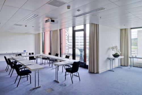 a conference room with tables and chairs and a whiteboard at Radisson Blu Hotel Zurich Airport in Kloten