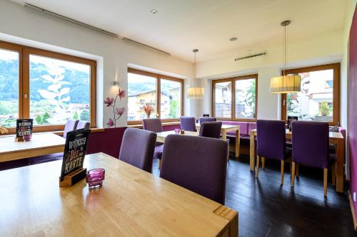 a restaurant with purple chairs and tables and windows at Zillertalerhof in Ried im Zillertal