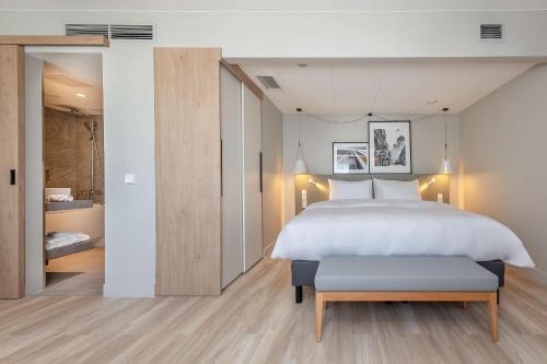 a bedroom with a large white bed and a bench at Radisson Hotel Kaunas in Kaunas