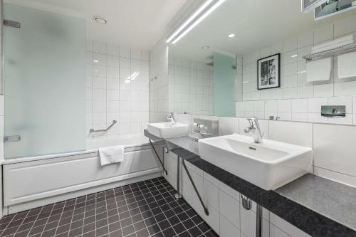 a white bathroom with two sinks and a bath tub at Radisson Hotel Kaunas in Kaunas