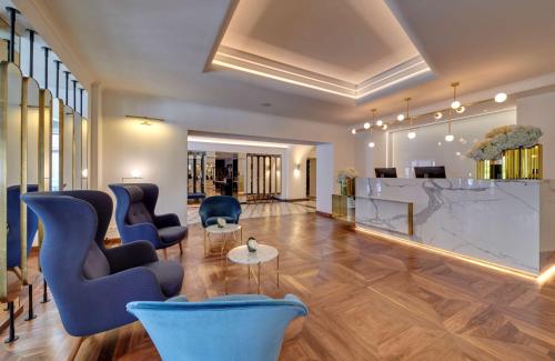 a lobby with blue chairs and a table in a building at Radisson Collection Astorija Hotel, Vilnius in Vilnius