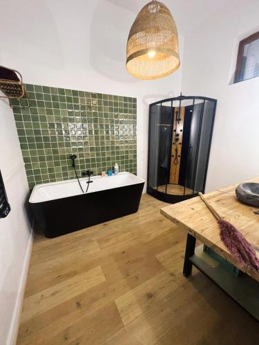 La salle de bains est pourvue d'une baignoire noire et de carrelage vert. dans l'établissement Appartement studio loft cosy centre st Etienne, à Saint-Étienne