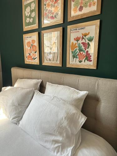 a bed with white pillows and framed pictures on a green wall at CABADOL - Appartement Aix centre historique - très calme - 50m cours Mirabeau in Aix-en-Provence
