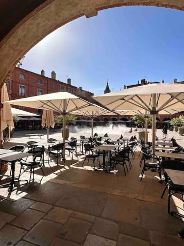 un groupe de tables et de chaises avec parasols dans l'établissement Charmant Studio 1- Hyper centre - Cœur de Montauban-Tous Commerces à pied, à Montauban