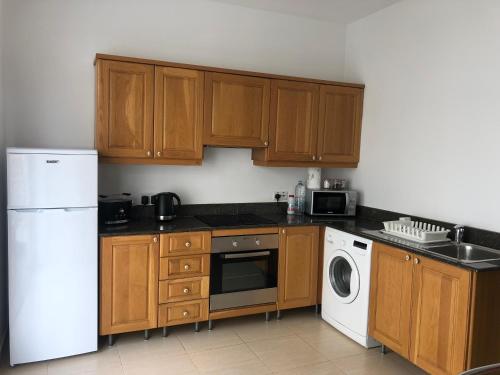cocina con armarios de madera, lavadora y secadora en Best location in Sliema, en Sliema