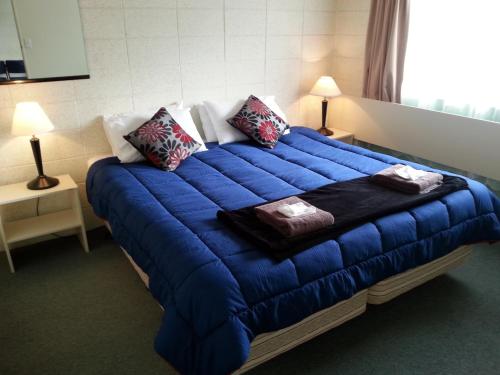 uma grande cama azul num quarto com duas lâmpadas em Motel Sierra em Whangarei