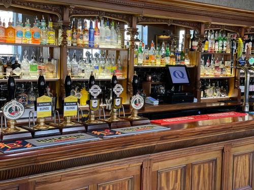 a bar with a lot of bottles of alcohol at The Queens Head, Parkside apartment 3 in Burley in Wharfedale