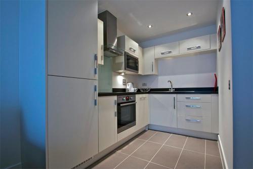 a kitchen with white appliances and blue walls at Apartment in Newbury Parkway Centre in Thatcham